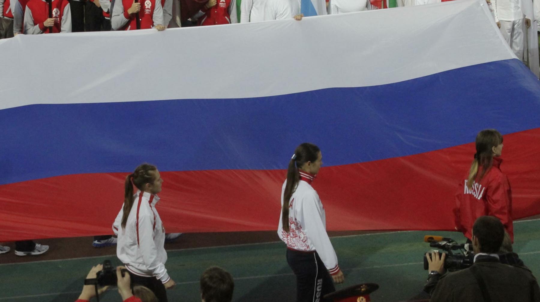 Российские спортсмены под флагом ссср. Спортсмены с флагом России. Российские спортсмены на пьедестале с флагом. Российских спортсменов лишили флага.