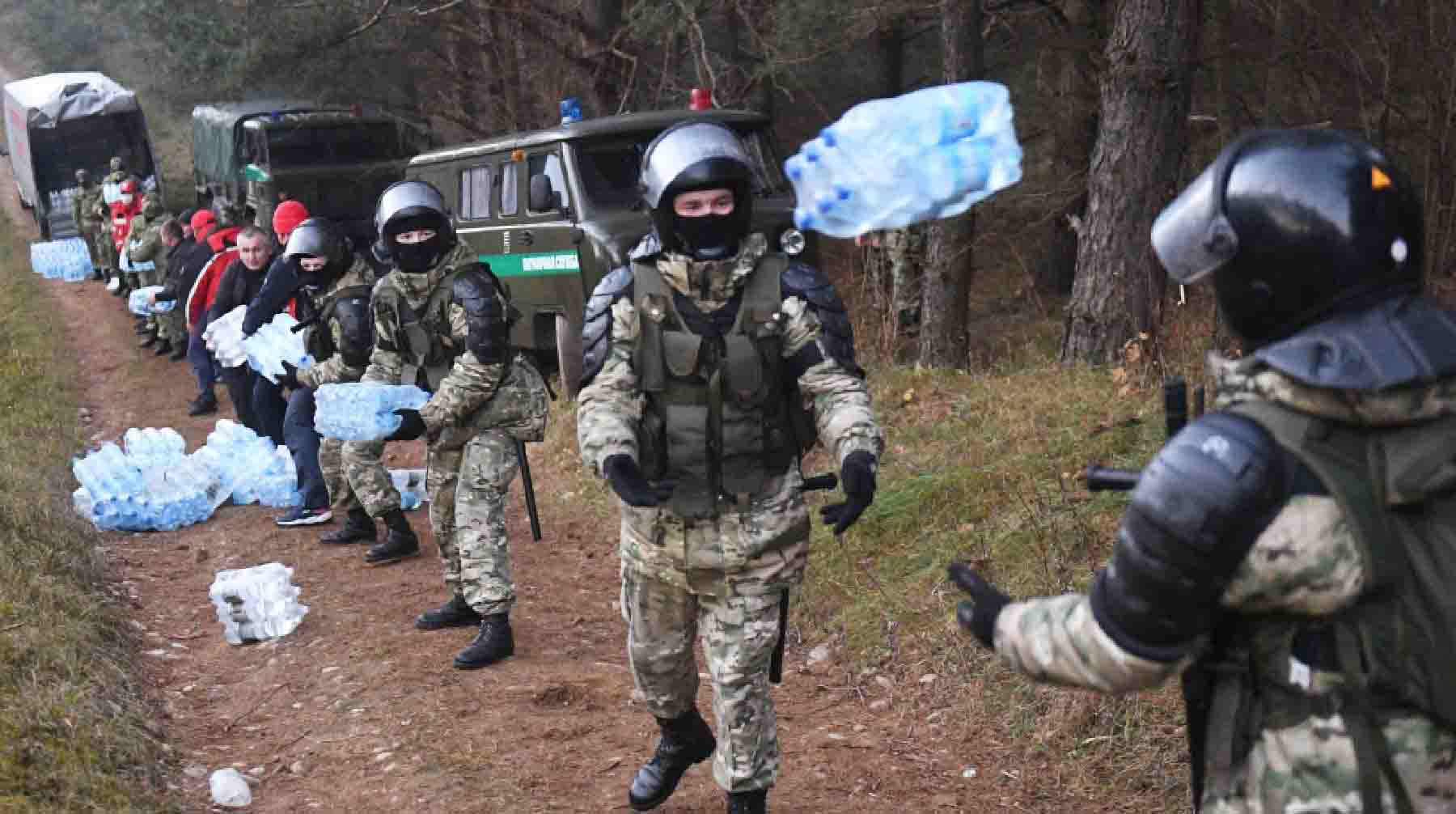 Сотрудники правоохранительных органов Белоруссии помогают разгружать воду, доставленную волонтерами, в лагере нелегальных мигрантов.