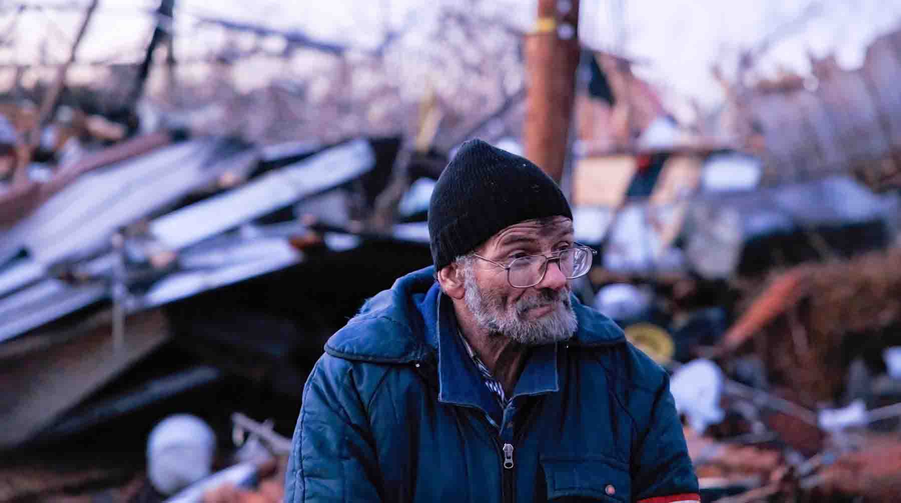 Местный житель стоит возле своего разрушенного дома