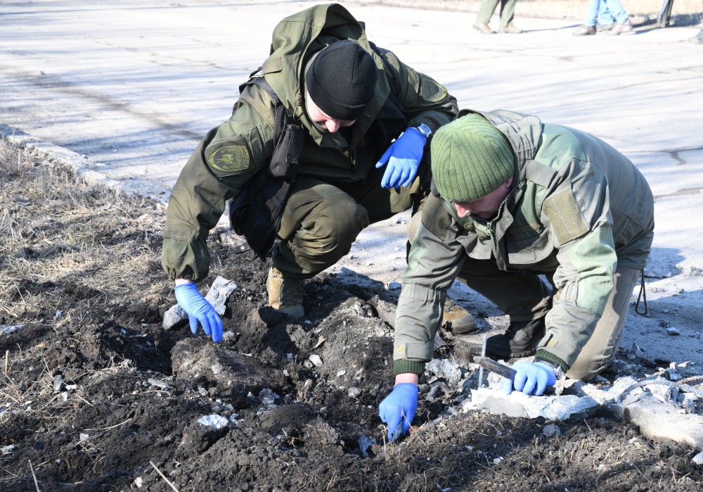 Сотрудники народной милиции ДНР осматривают место взрыва в Петровском районе Донецка после обстрела.