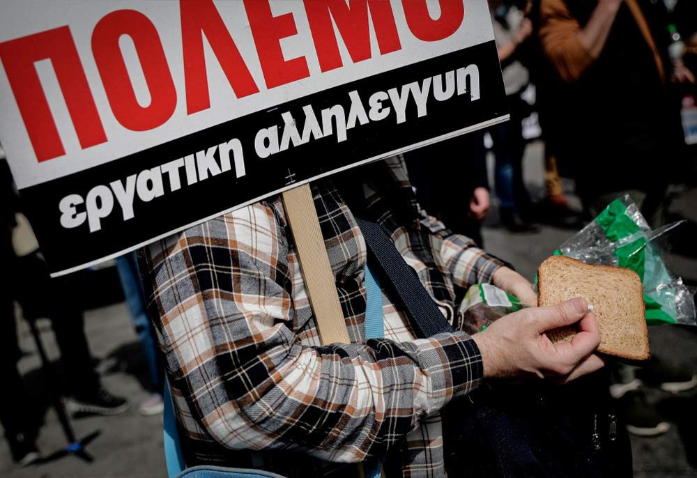 Участник забастовки профсоюзов с плакатом и хлебом в руках.