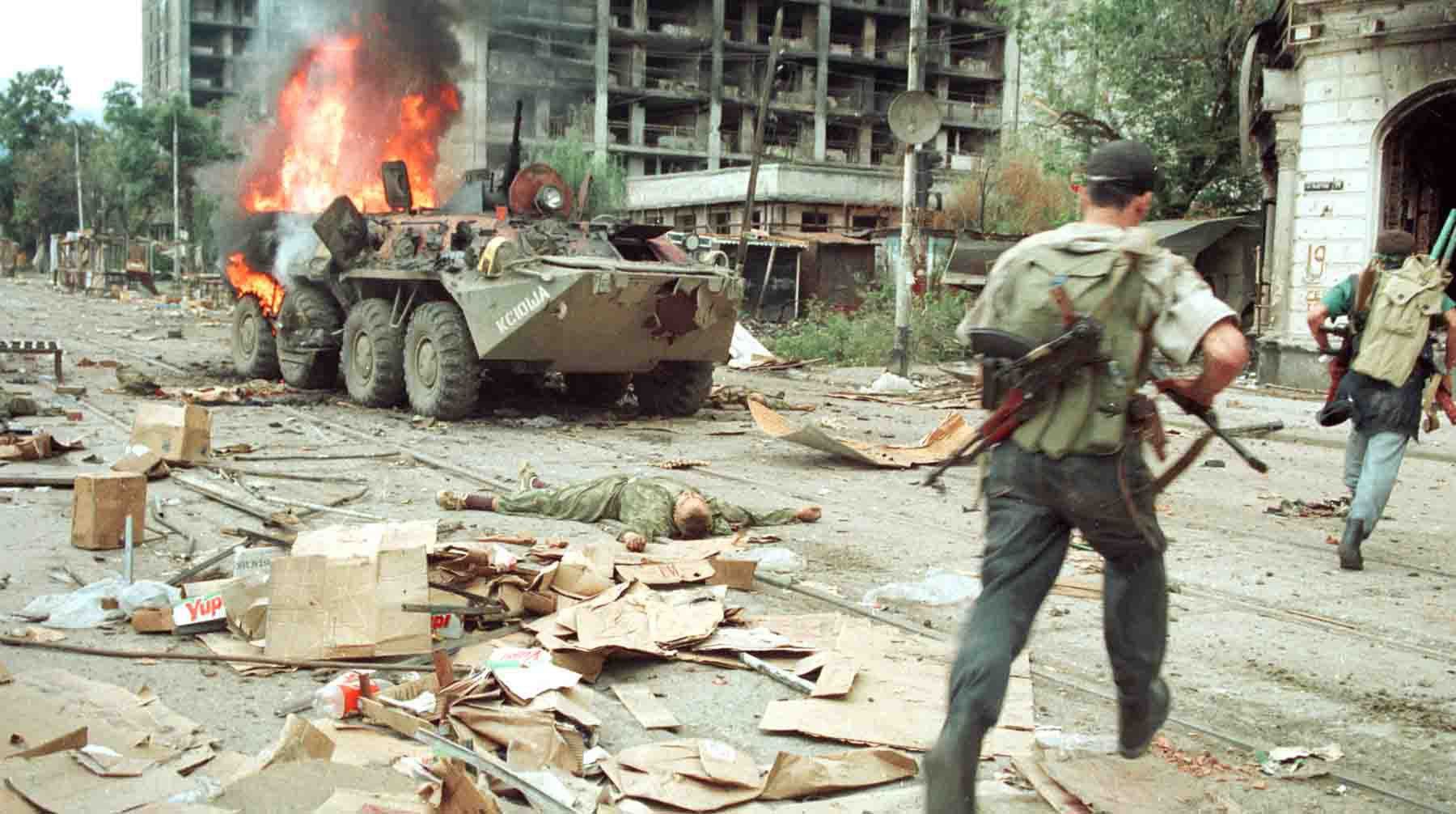 1996 год. Грозный, Россия. Чеченский повстанец проходит мимо горящего российского бронетранспортера.